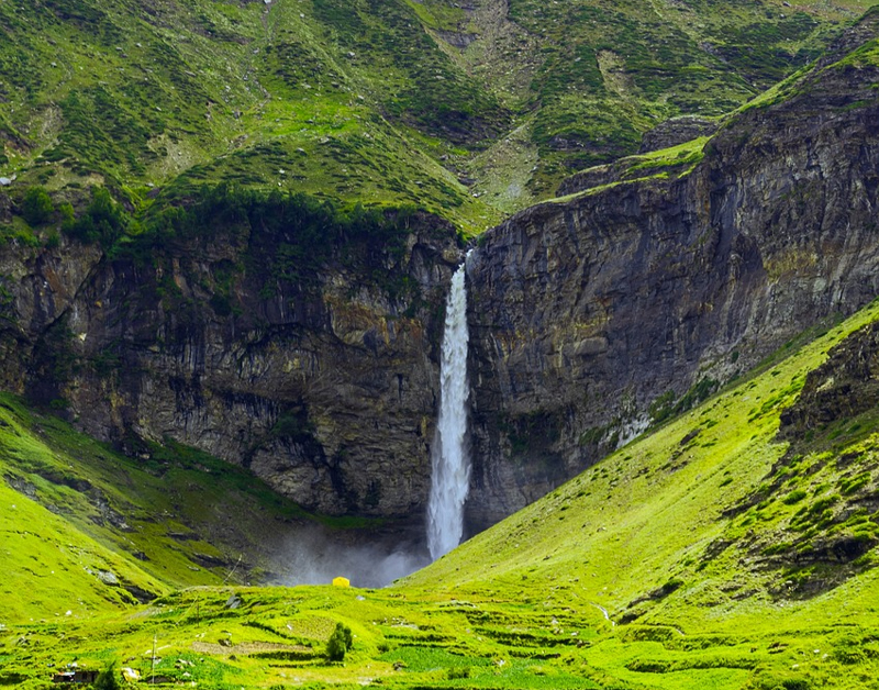 A picturesque waterfall flowing through a lush green valley, creating a serene and captivating scene.