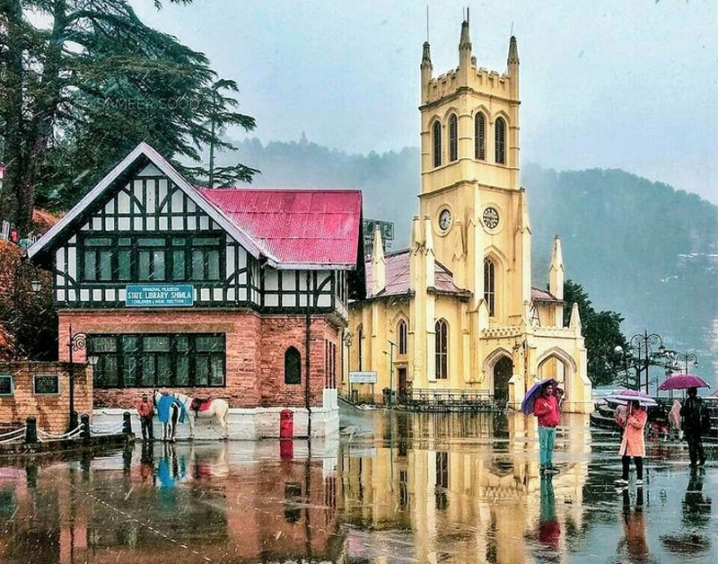 People walking through rain in front of church.