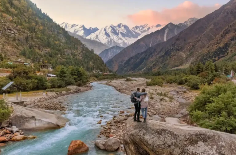 Couple gazing at snowy mountains and river in lush valley