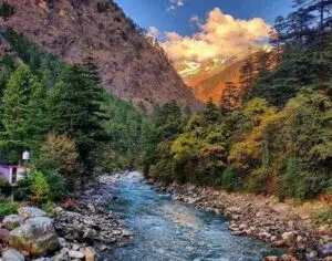 Scenic Himalayan river valley with lush forests and snow-capped mountains