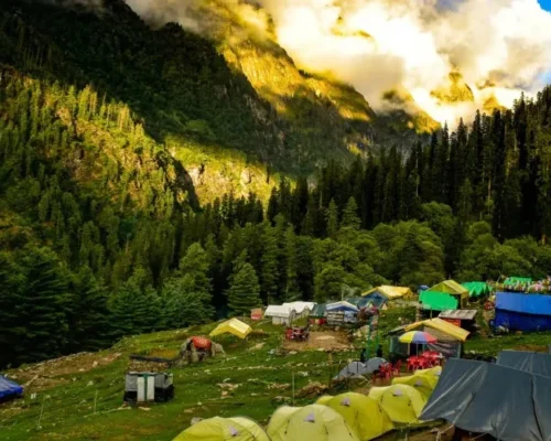 Group of colorful tents in a lush green valley with mountains in the background