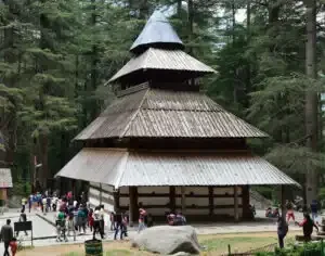 Traditional wooden temple with people visiting in a forest setting
